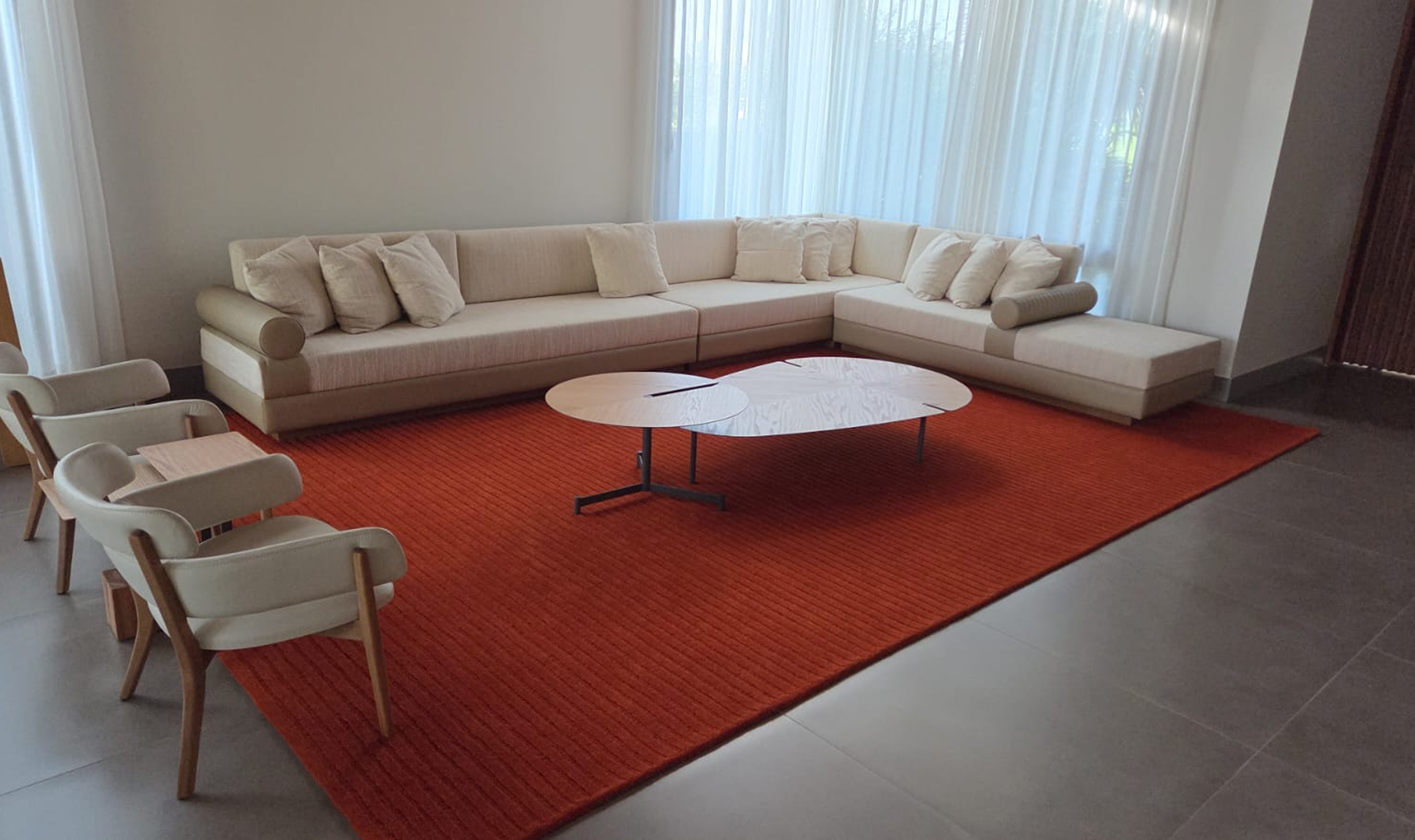 Sala com sofá bege, poltronas e tapete vermelho